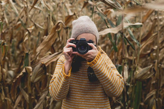 Autumn photographer taking picture wearing yellow wool jumper with wide sleeves and thick cuffs